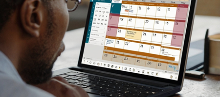 A business owner using Microsoft Bookings on a laptop, with an online calendar and appointment slots visible.